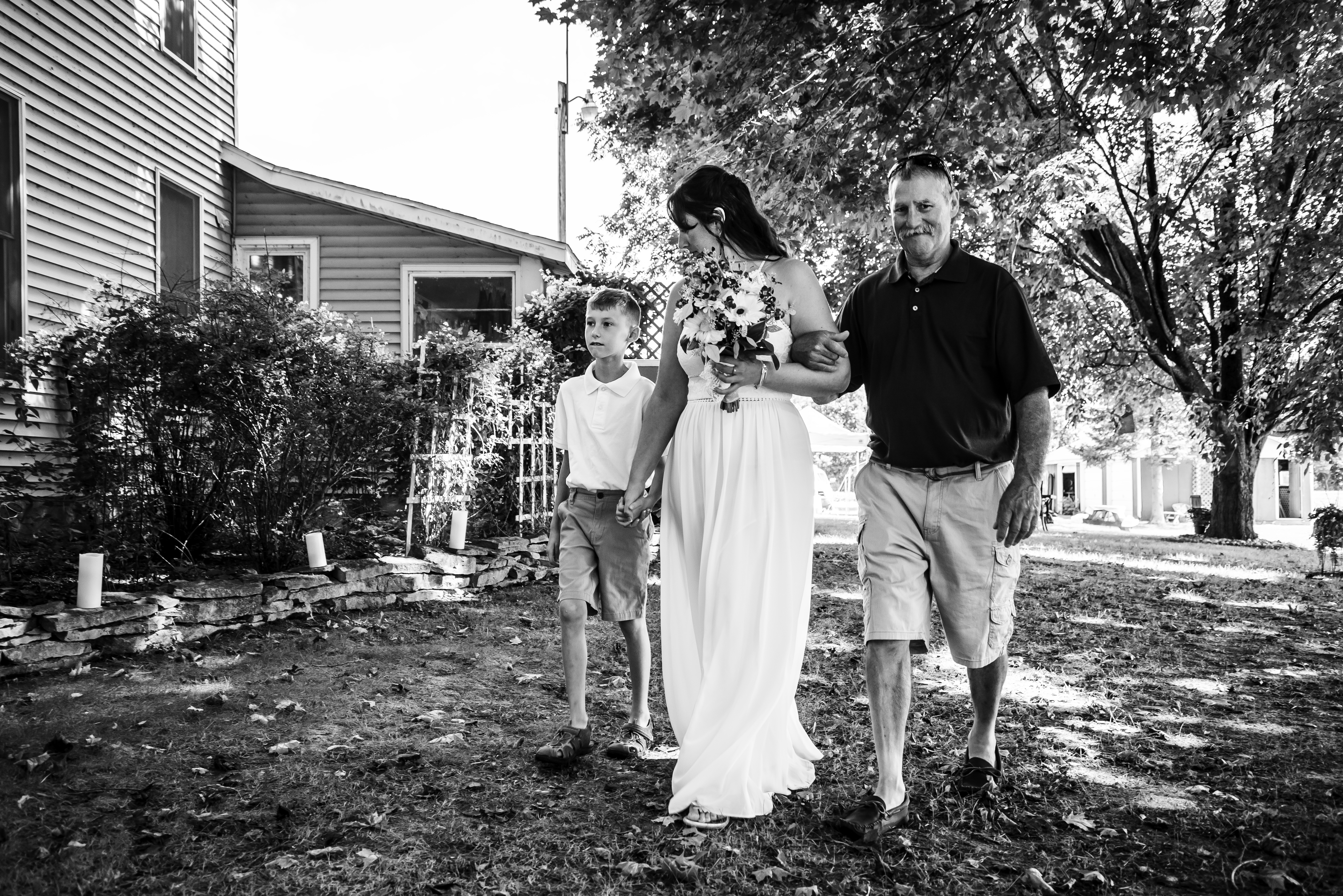 Bride walking across the lawn towards the ceremony with family