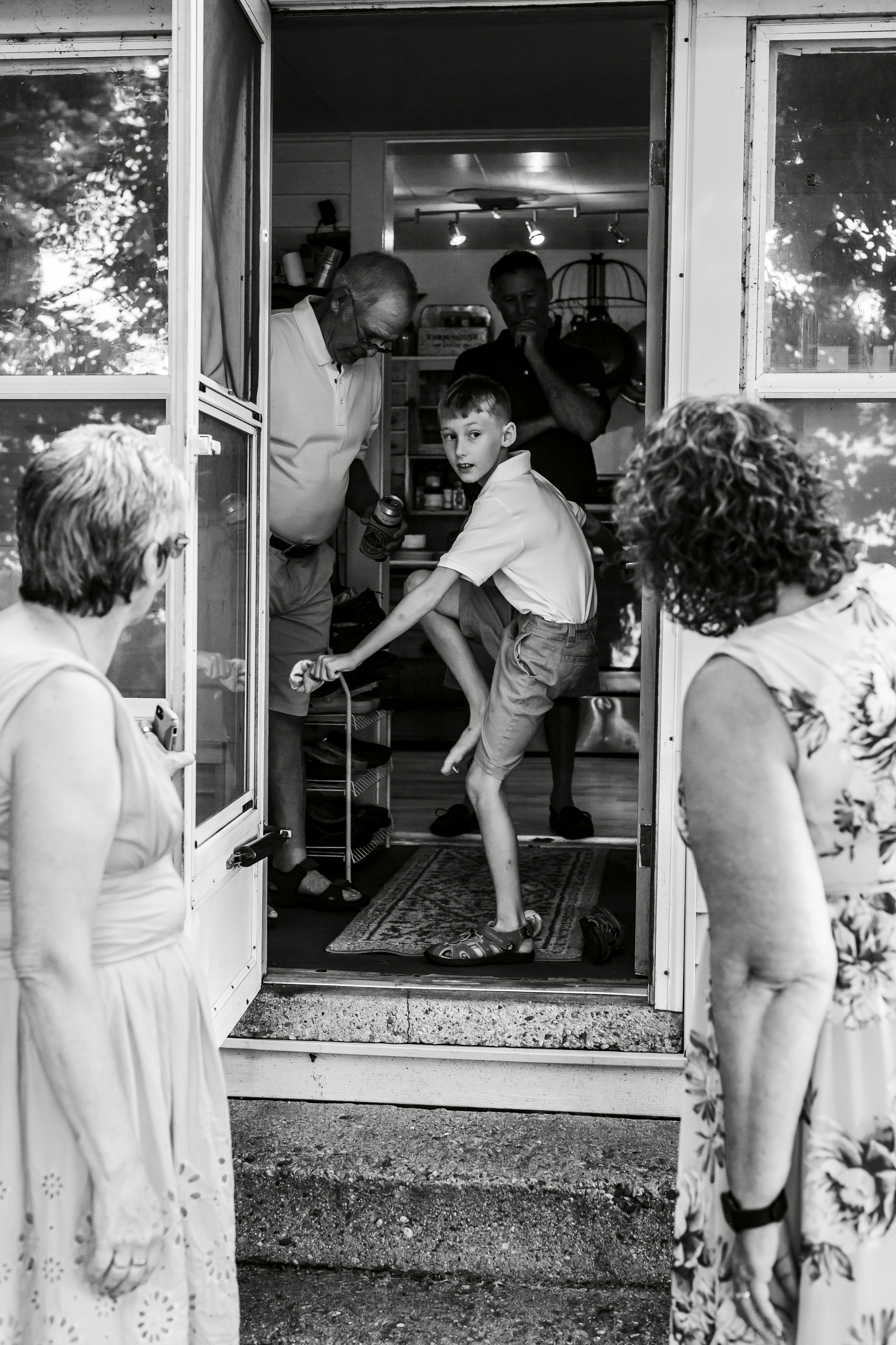 Little boy putting shoes on in a doorway