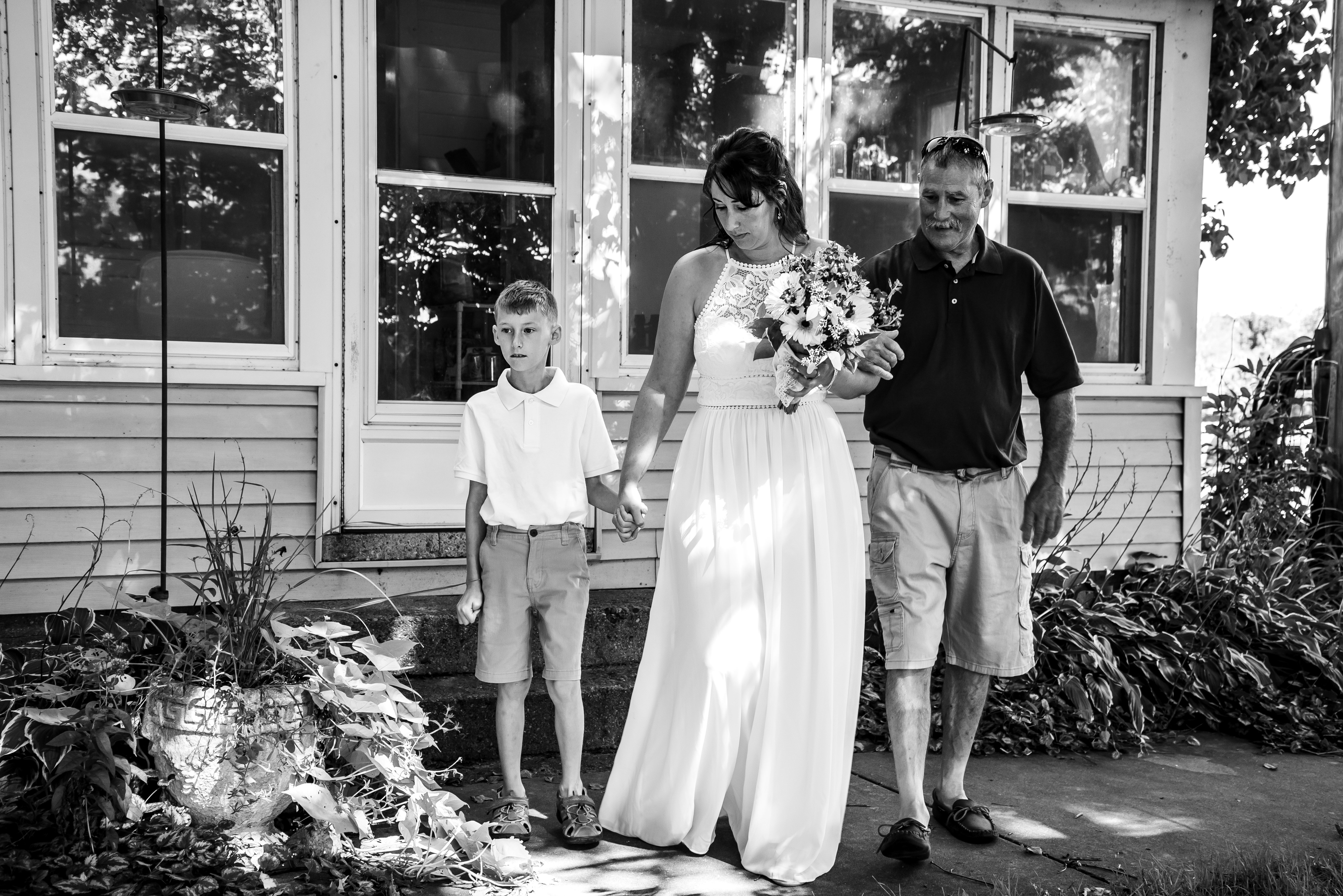Bride with family holding bouquet walking towards the ceremony