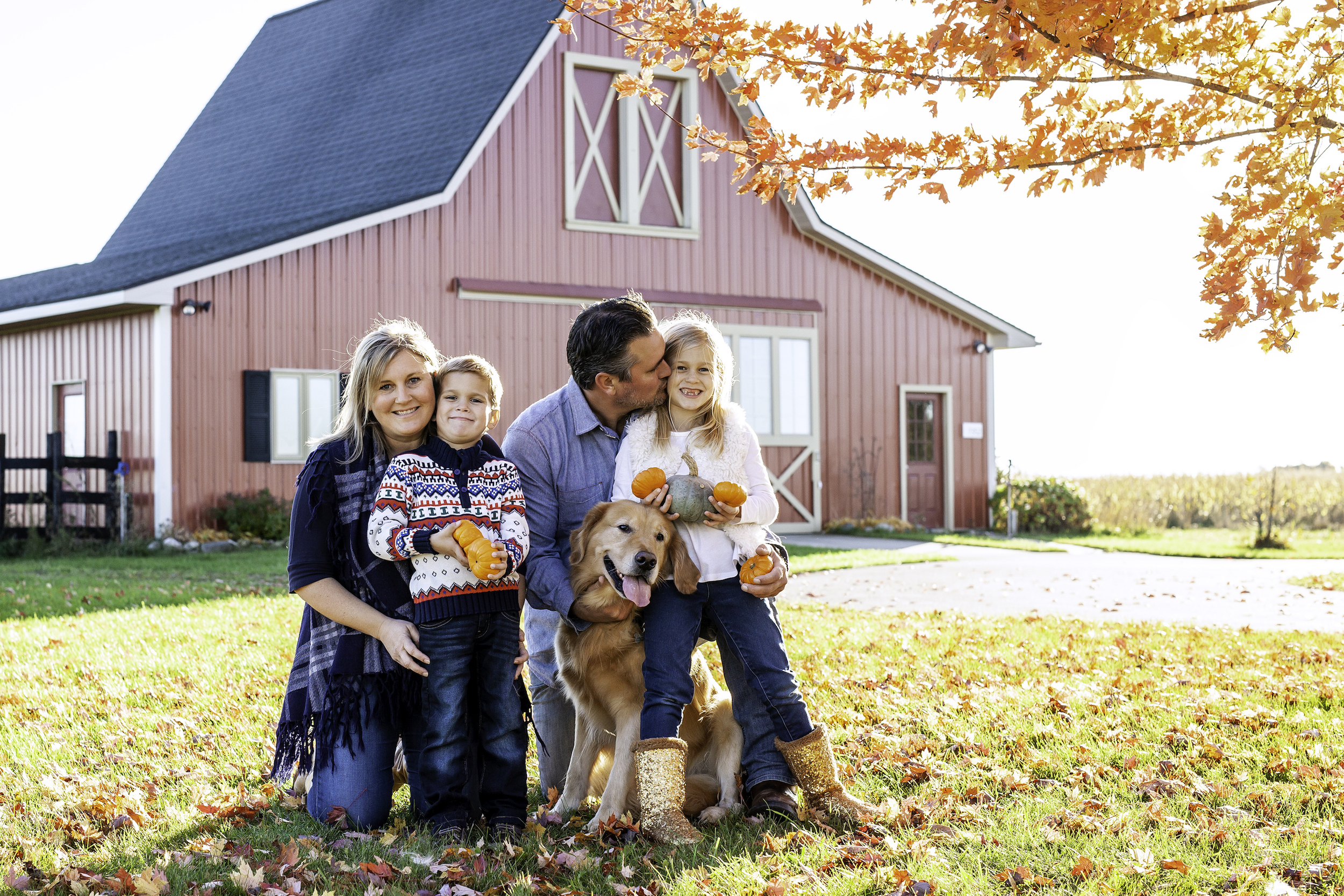 Family portrait with a dog in front of a barn