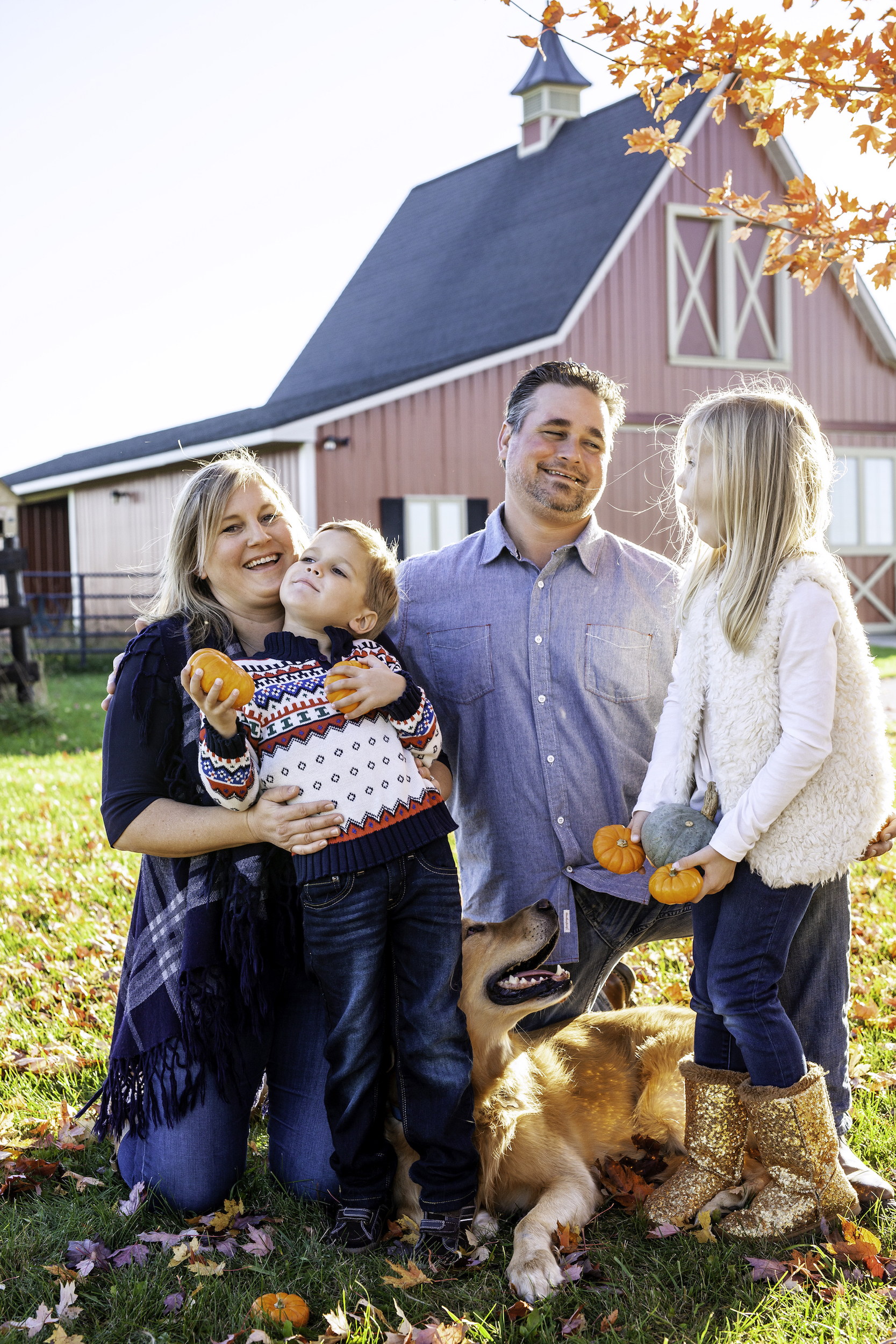 Family laughing together in front of a barn