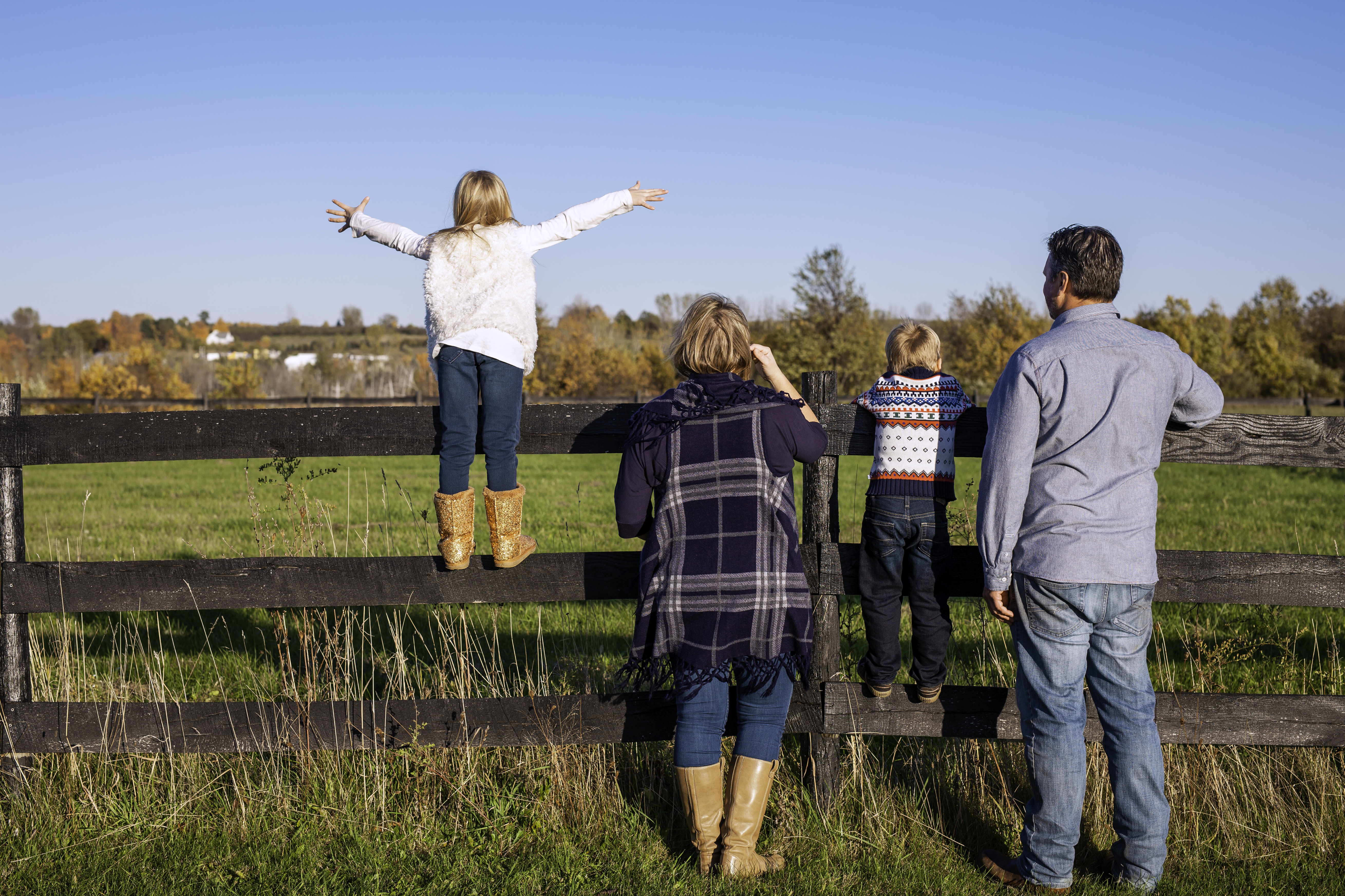 Family facing away towards a fence and a field