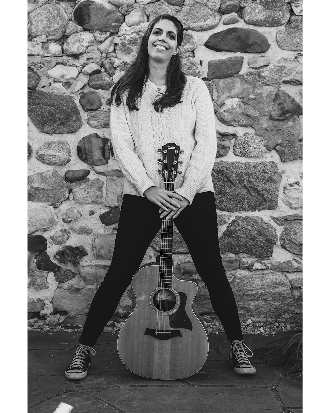 Black and white image of a Music Teacher smiling with her guitar
