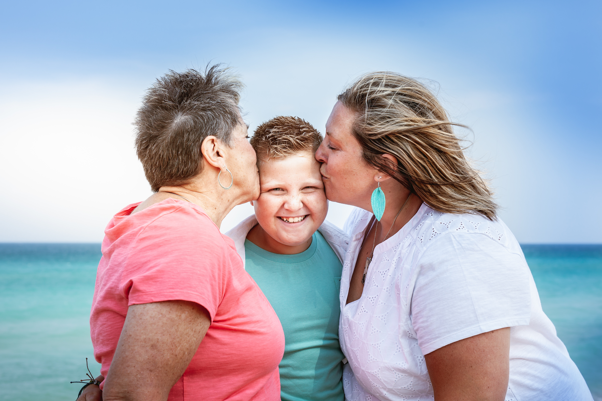 Two women kissing child's head, one from each side
