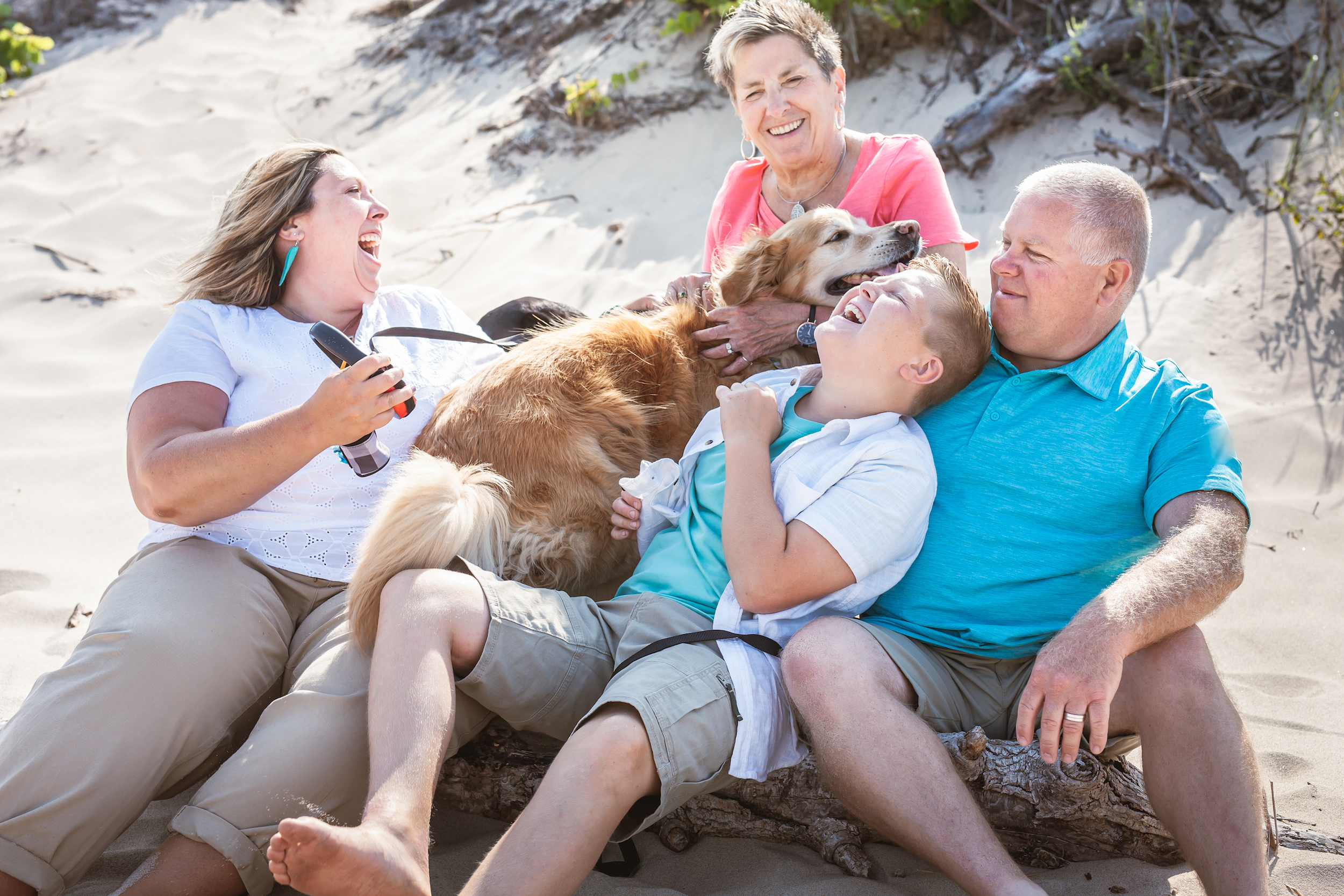 Family laughing on beach with dogs
