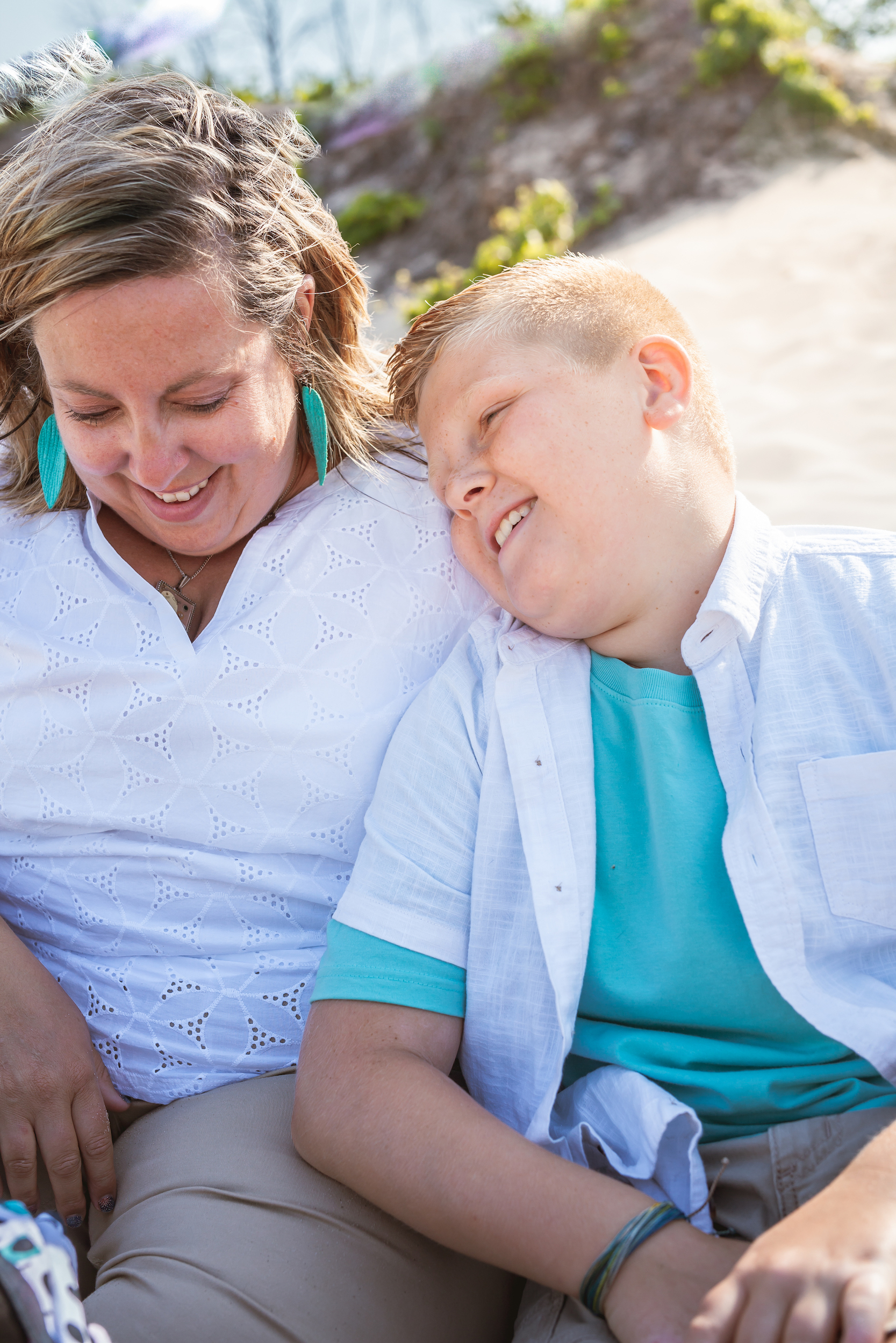 Child leaning against woman sitting on beach