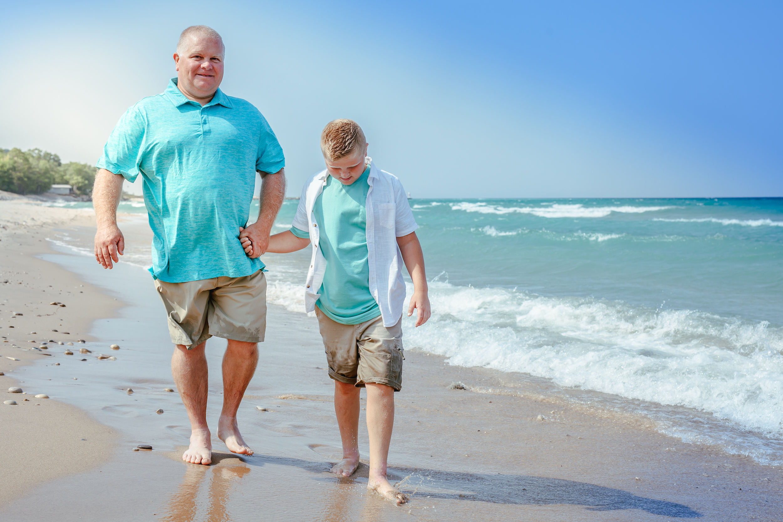 Man and child walking on the beach holding hands