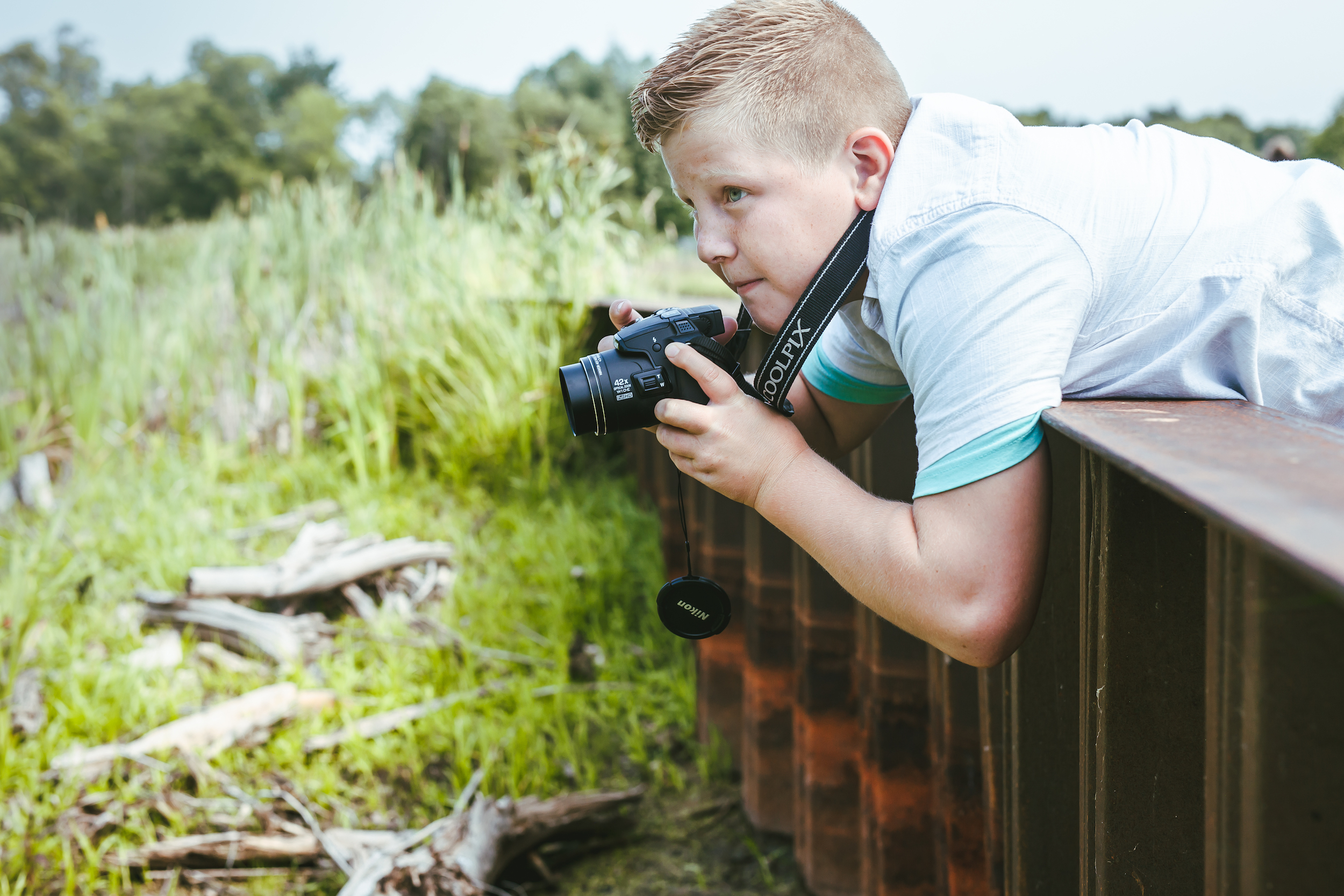 Child with camera strapped around their neck leaning over and edge