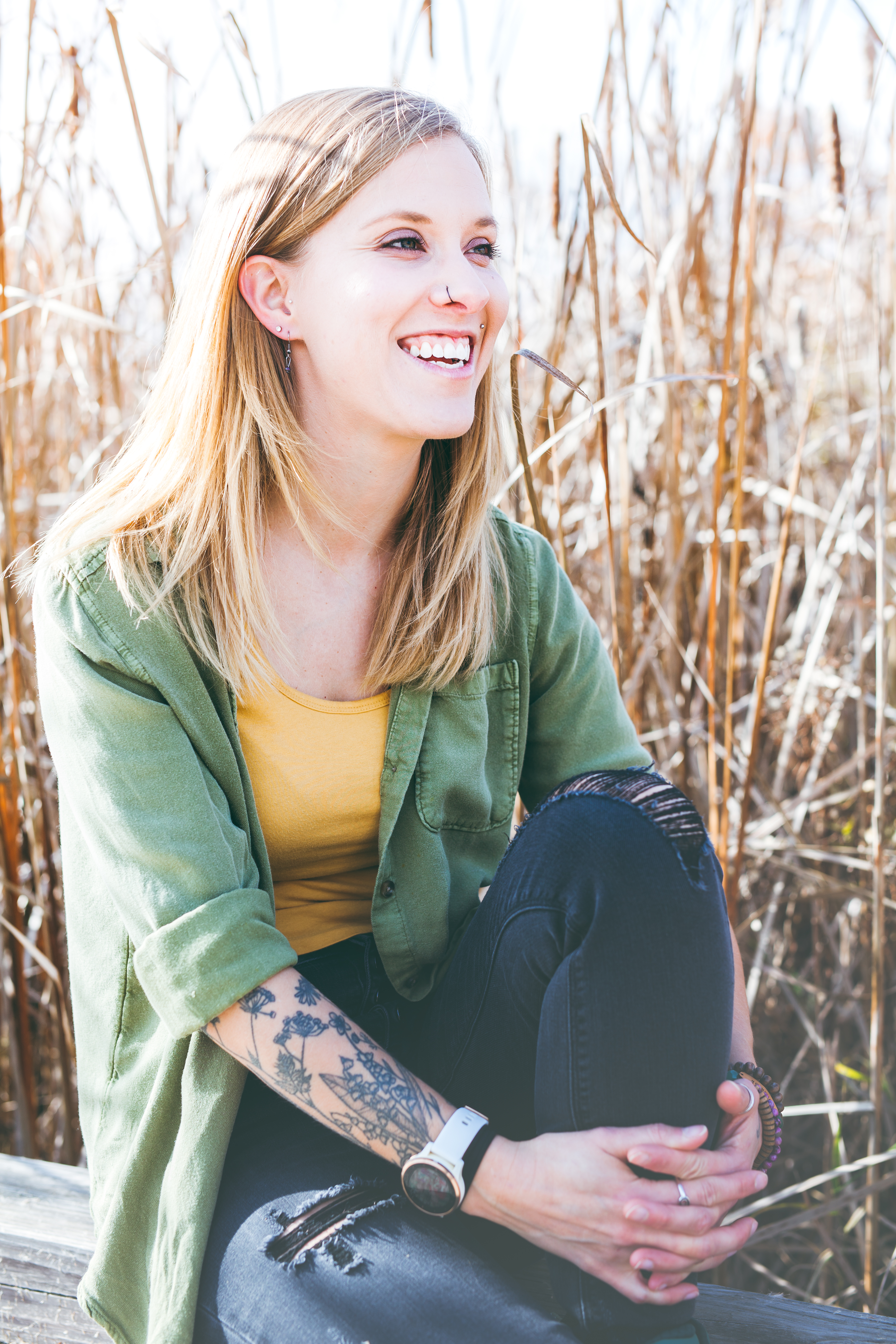 Woman sitting by tall grass and smiling