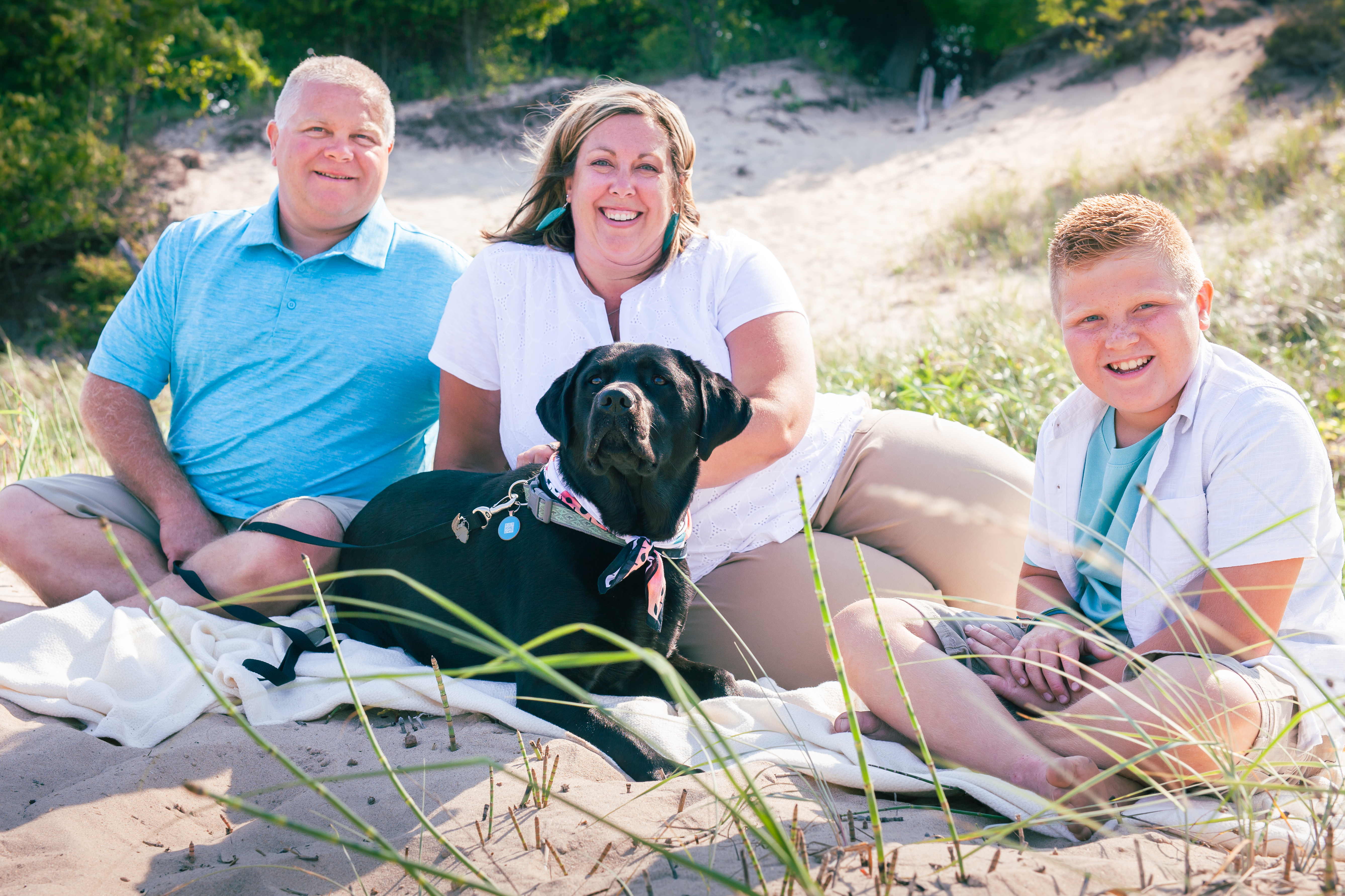 Family smiling on blanket with a dog