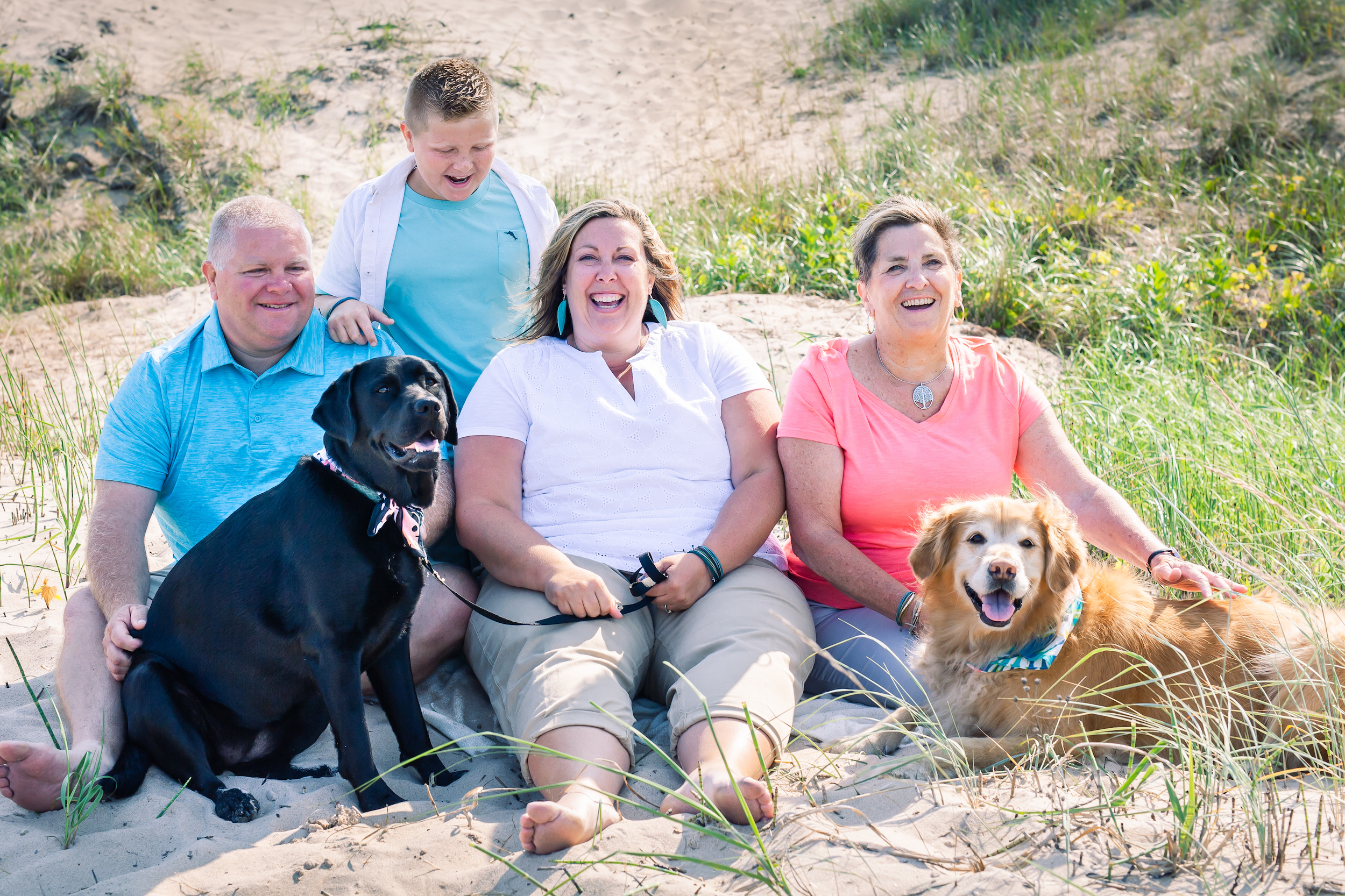 Family smiling on the beach with two dogs